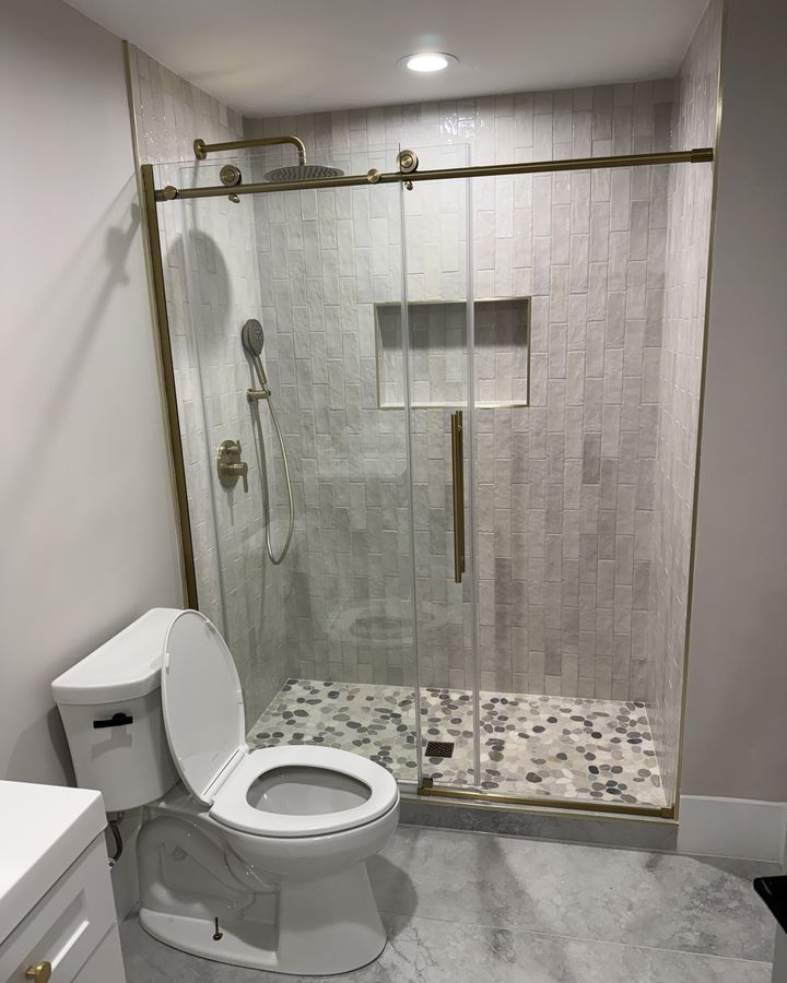 Bathroom remodel with white tile shower, pebble floor and brushed gold fixtures