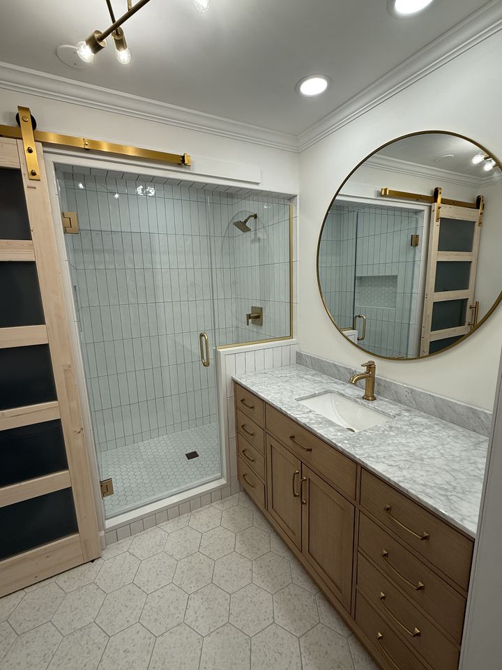Bathroom with barn door, tiled shower and round mirror