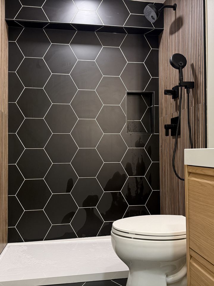 Black hexagon tile shower with wood-look wall